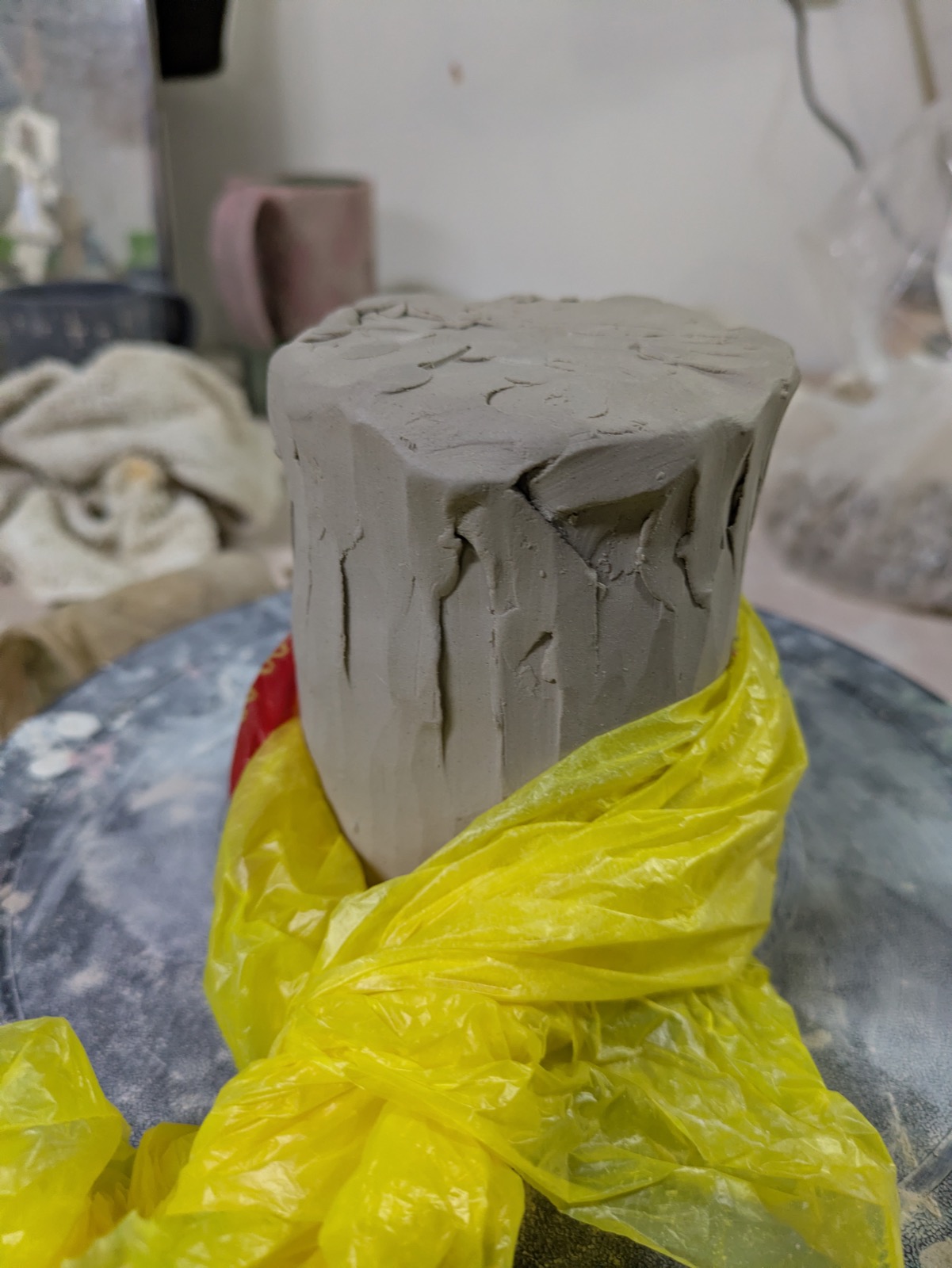 The carved form wrapped in its yellow plastic blanket on the wheel