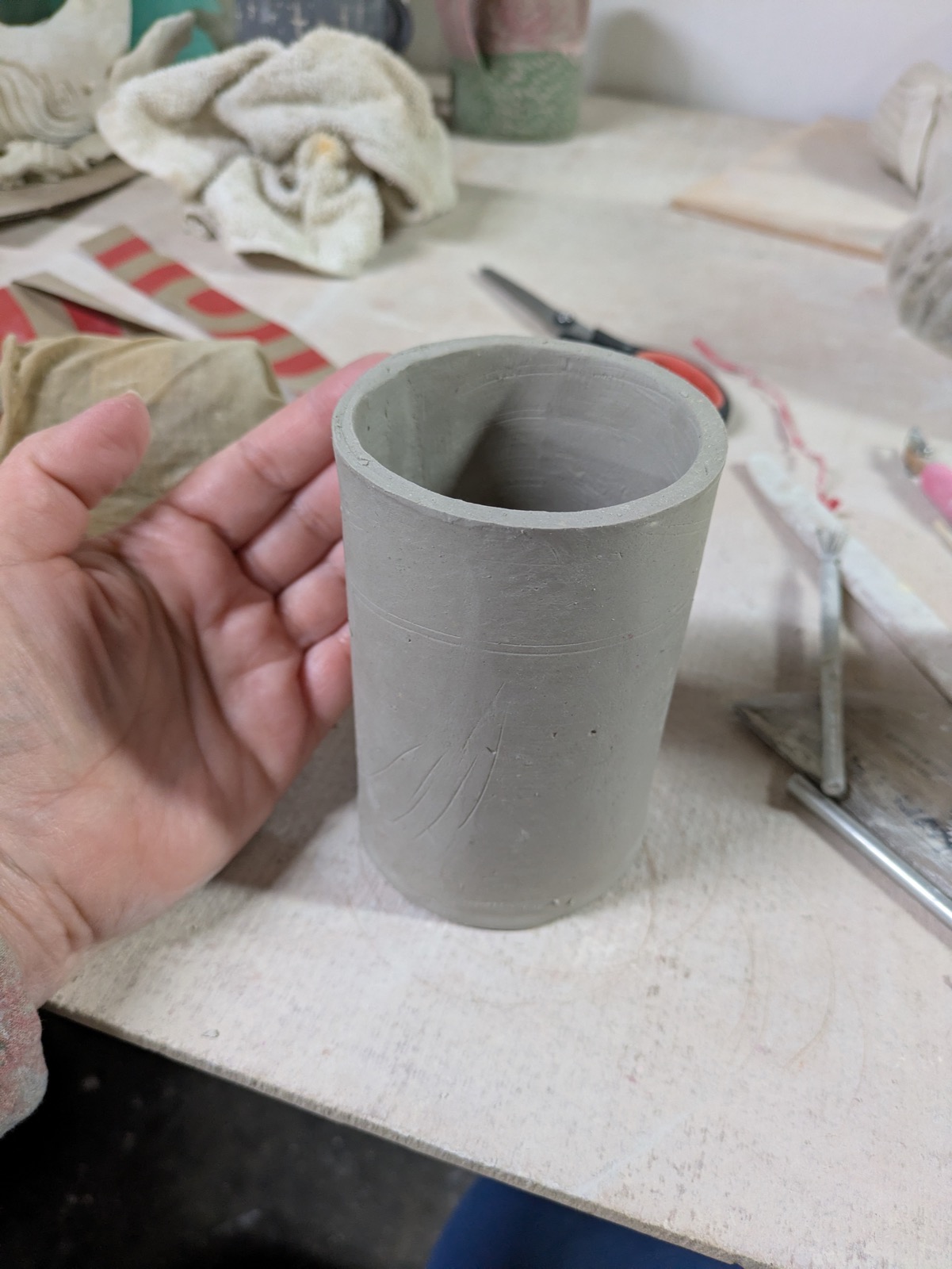 A small clay cylinder held in one hand — the starting point