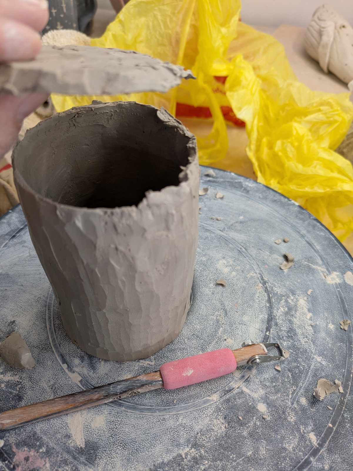 Hollowing out the form, hand reaching in with a pink tool nearby
