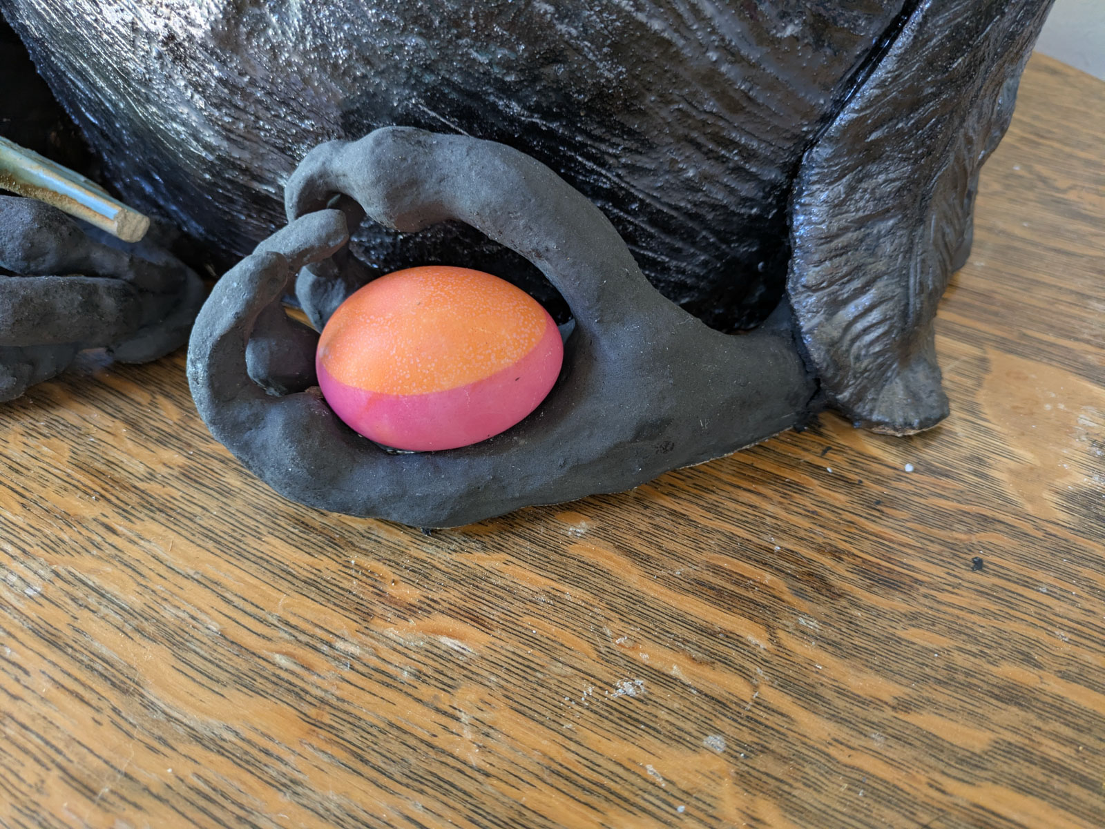 easter egg fitting perfectly in crow statue's foot